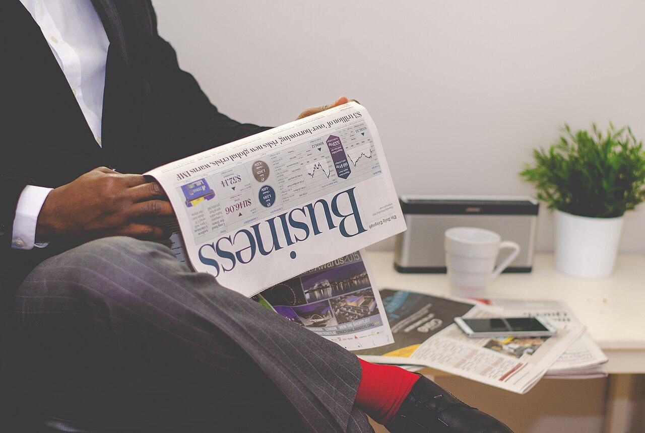 A person in a suit reading the business section of a newspaper